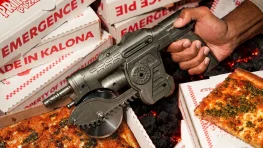Gears of War: E-Day Gets an ‘Emergence Pie’ and Prototype Lancer Pizza Cutter 4 A hand holds a Prototype Lancer pizza cutter above Emergence Pie slices and branded boxes.