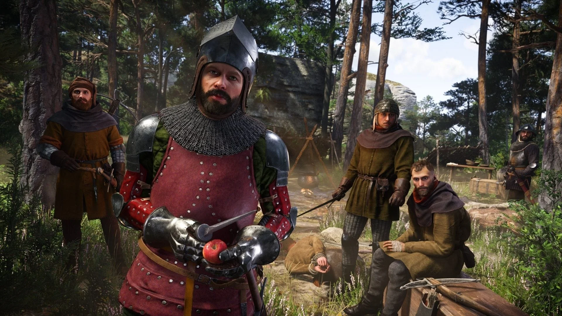 An armored man holds an apple and knife among a group in a forest in Kingdom Come: Deliverance 2.