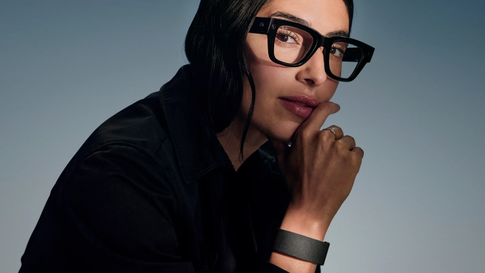A woman wearing Meta Ray-Ban Display glasses with Meta Neural Band visible